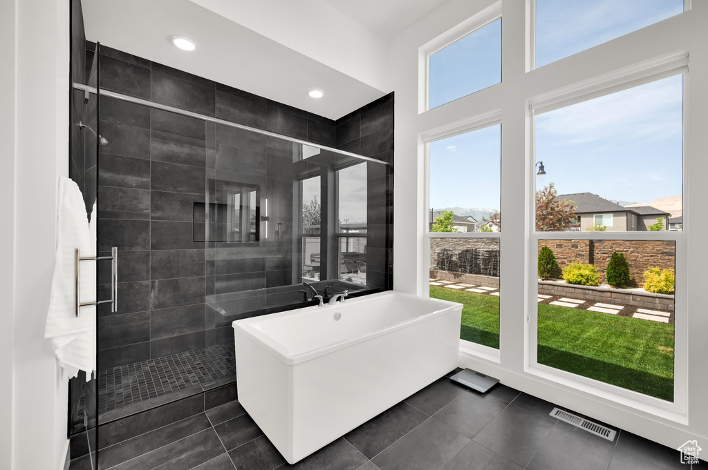 Full bath with healthy amount of natural light, a stall shower, a freestanding tub, and recessed lighting