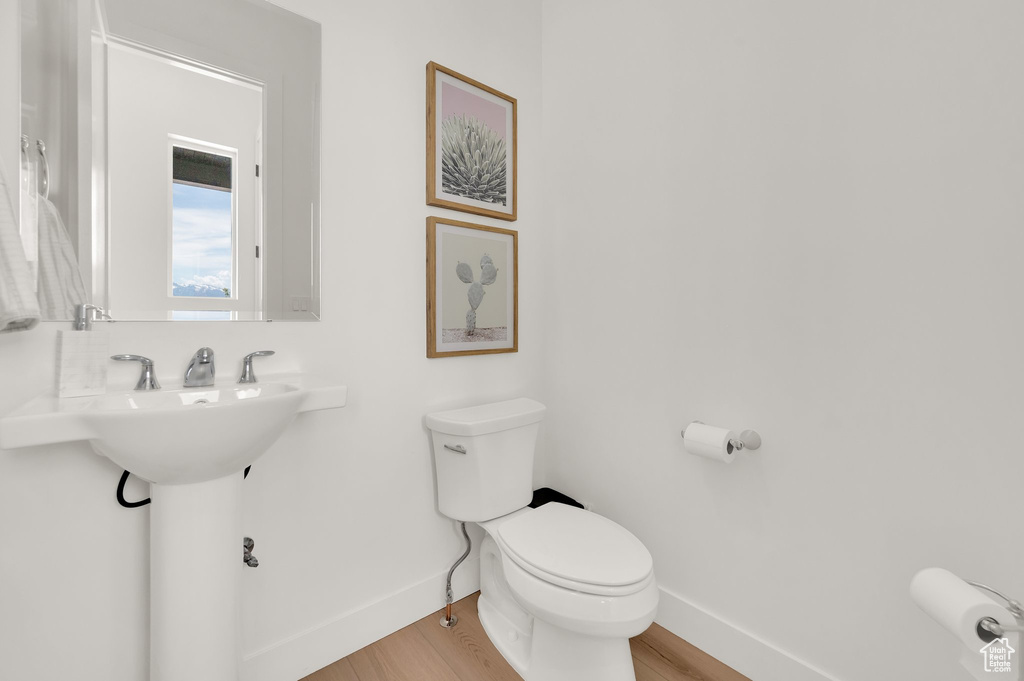 Bathroom with toilet, baseboards, and wood finished floors