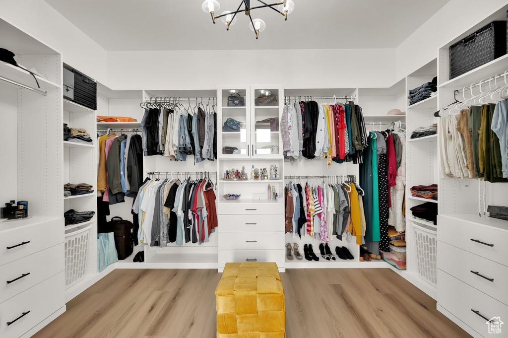 Walk in closet featuring light wood-style floors and a chandelier