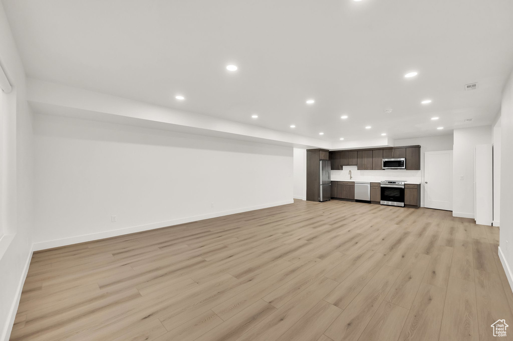 Unfurnished living room featuring recessed lighting, baseboards, and light wood-style flooring