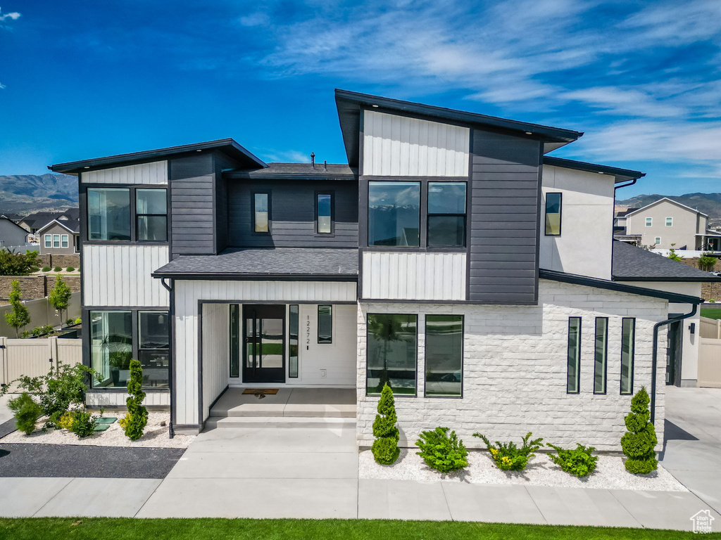 Modern home featuring stone siding, roof with shingles, and a mountain view