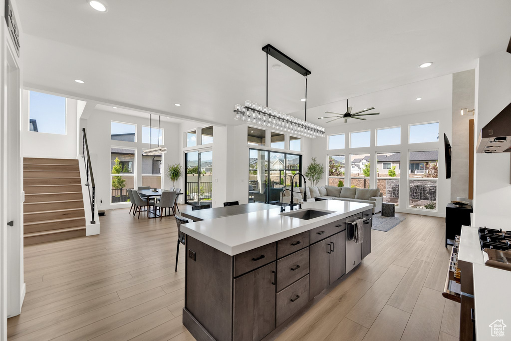 Kitchen with a sink, a ceiling fan, dark brown cabinets, open floor plan, and light countertops