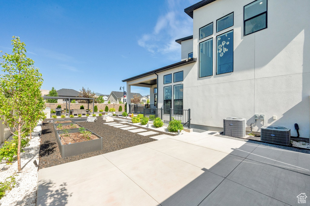 View of patio featuring a garden, central air condition unit, and a residential view
