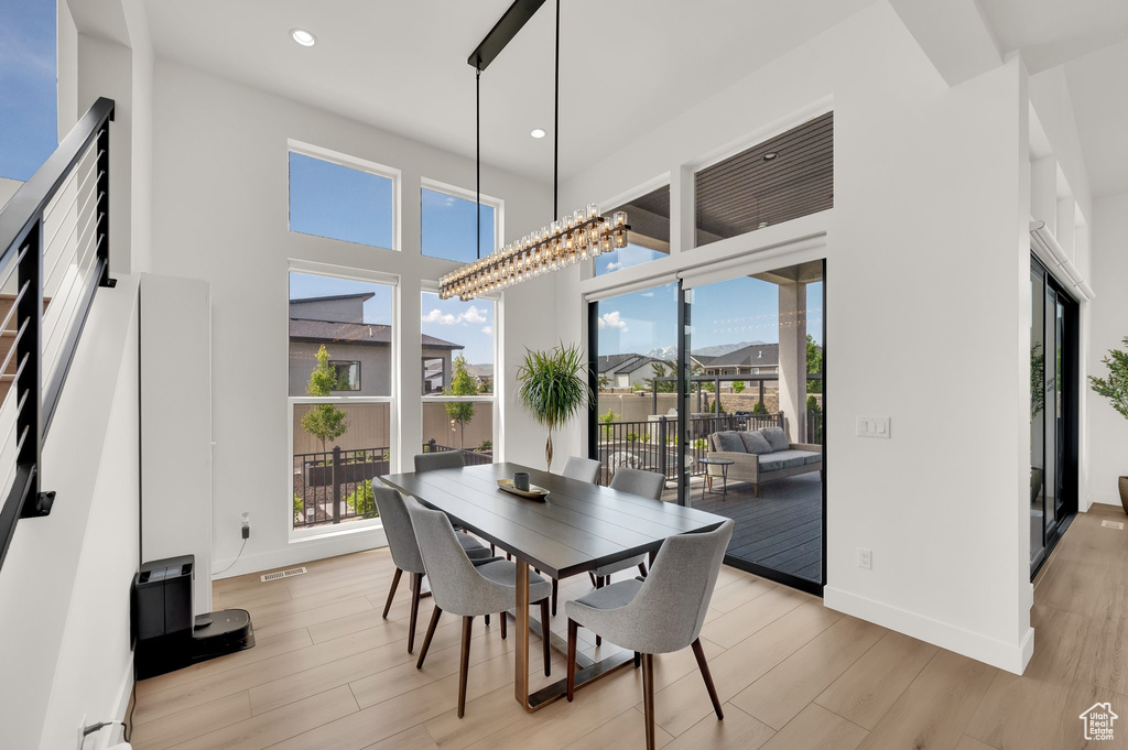 Dining room featuring healthy amount of natural light, light wood-style flooring, recessed lighting, baseboards, and a towering ceiling