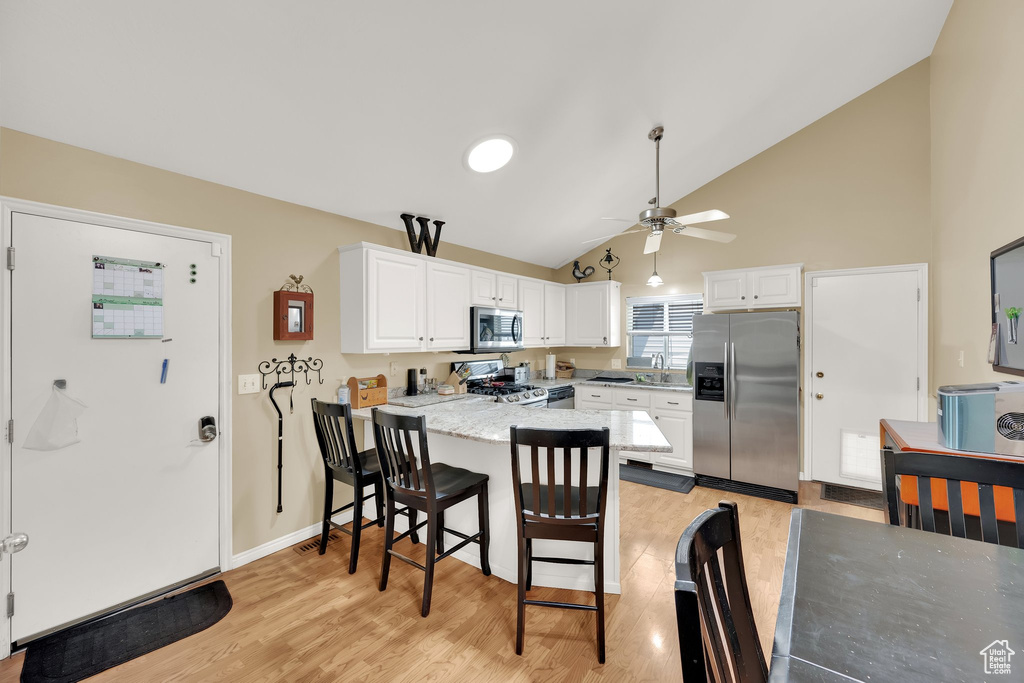 Kitchen with stainless steel appliances, a peninsula, a sink, a ceiling fan, and white cabinets