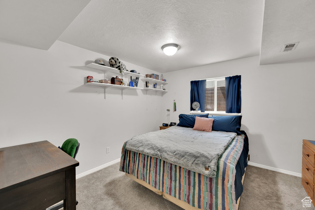 Carpeted bedroom featuring baseboards and a textured ceiling