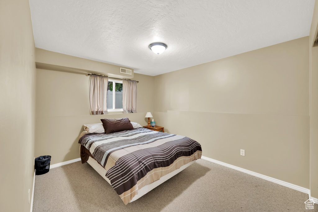 Bedroom with baseboards, carpet floors, and a textured ceiling