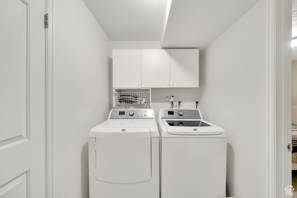 Washroom featuring cabinet space and washing machine and clothes dryer