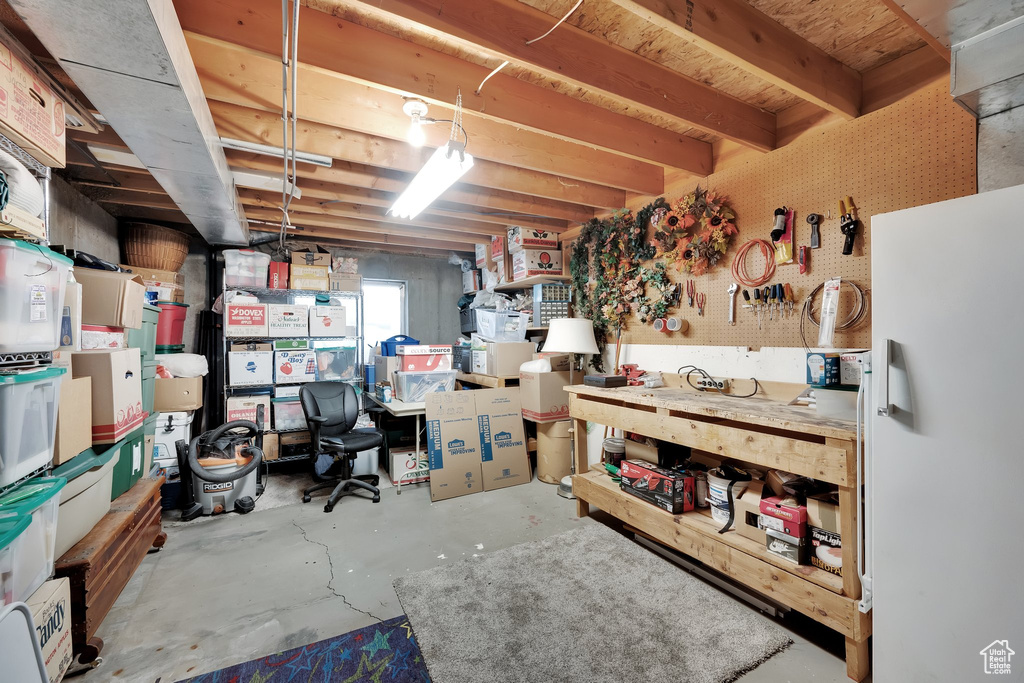 Basement featuring freestanding refrigerator and a workshop area
