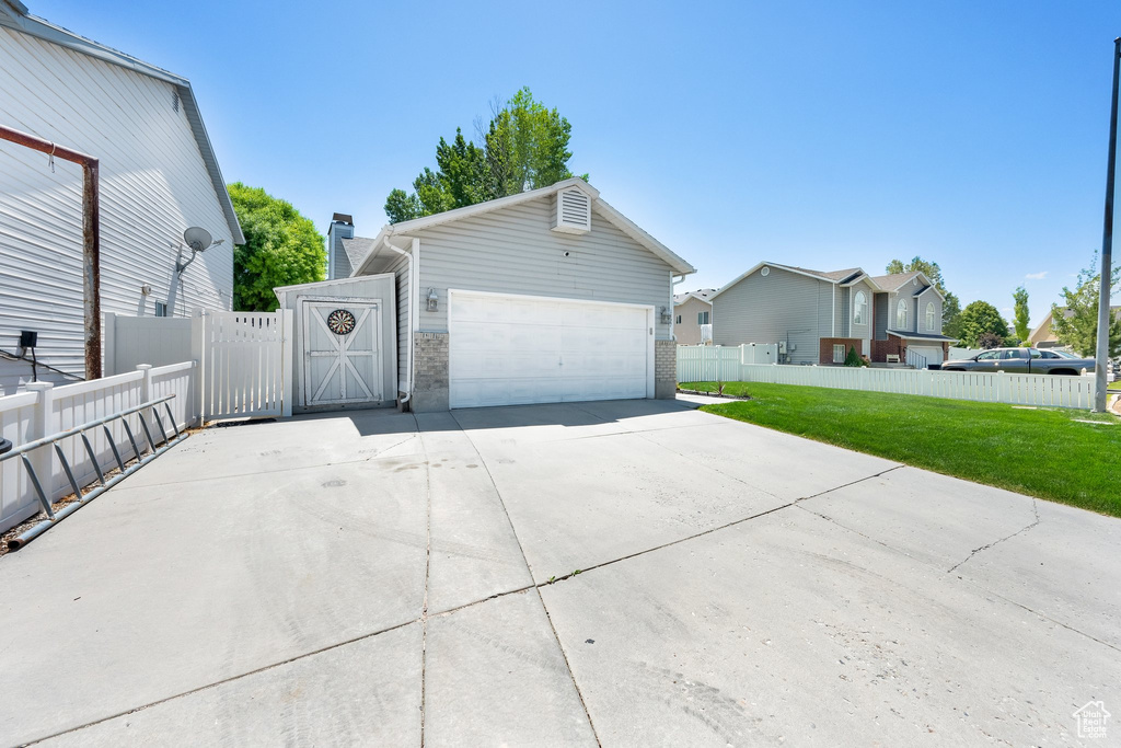 View of property exterior featuring driveway, a gate, a garage, and a chimney
