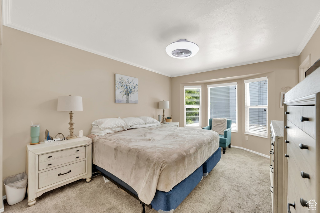 Bedroom with ornamental molding, light colored carpet, and baseboards