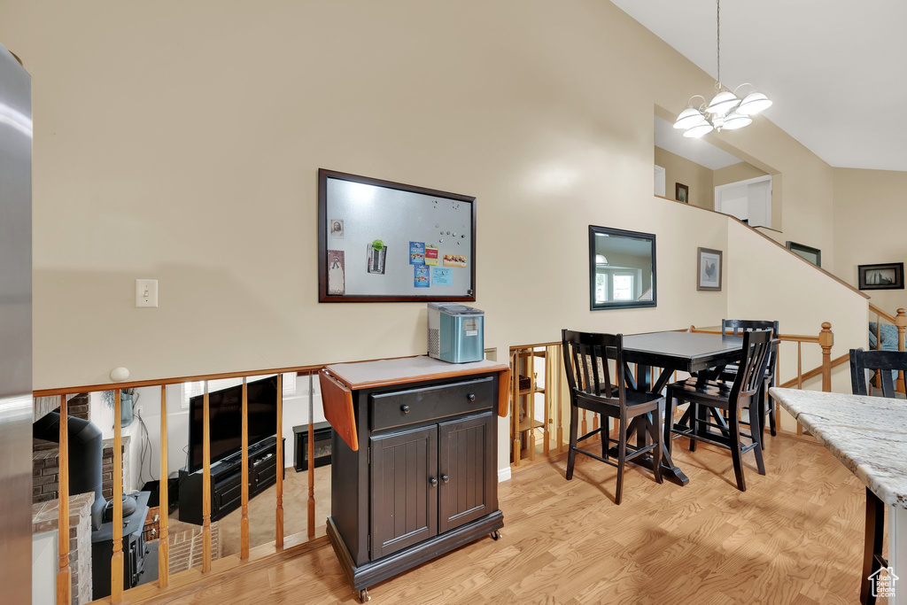 Dining area with light wood finished floors, a chandelier, and stairs