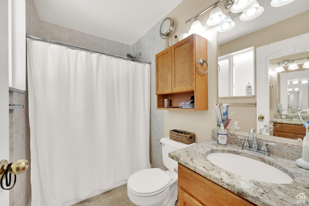 Bathroom with vanity, toilet, curtained shower, and tile patterned floors
