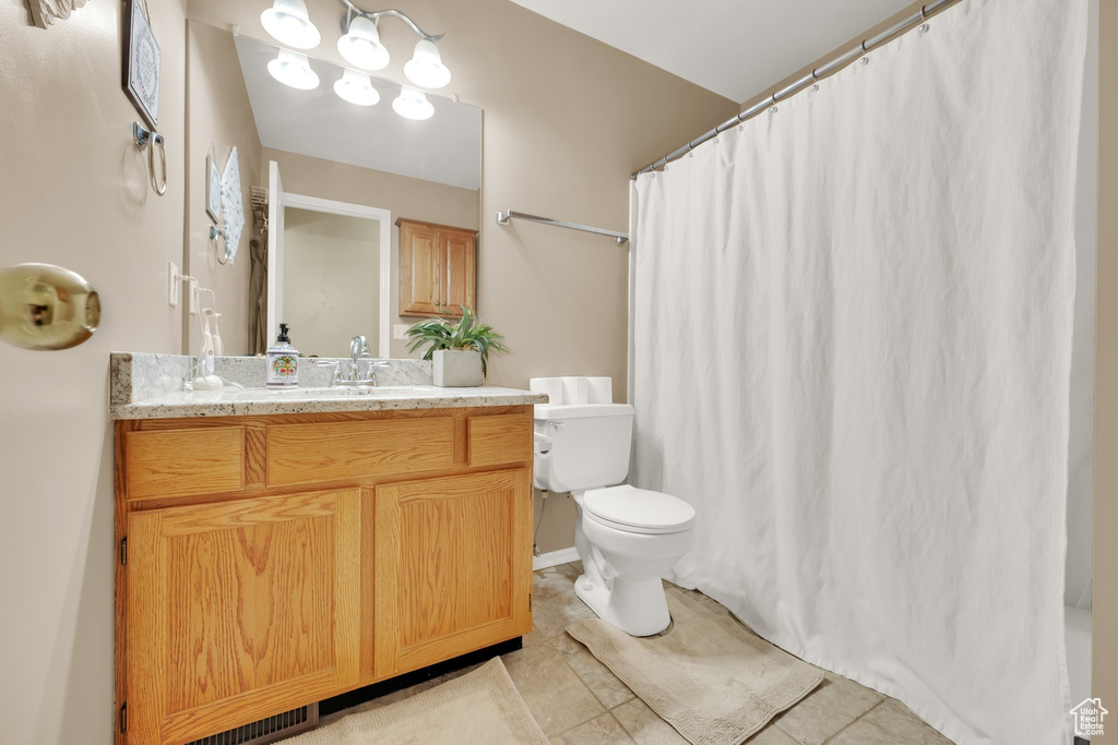 Bathroom with vanity, toilet, tile patterned floors, and a shower with shower curtain