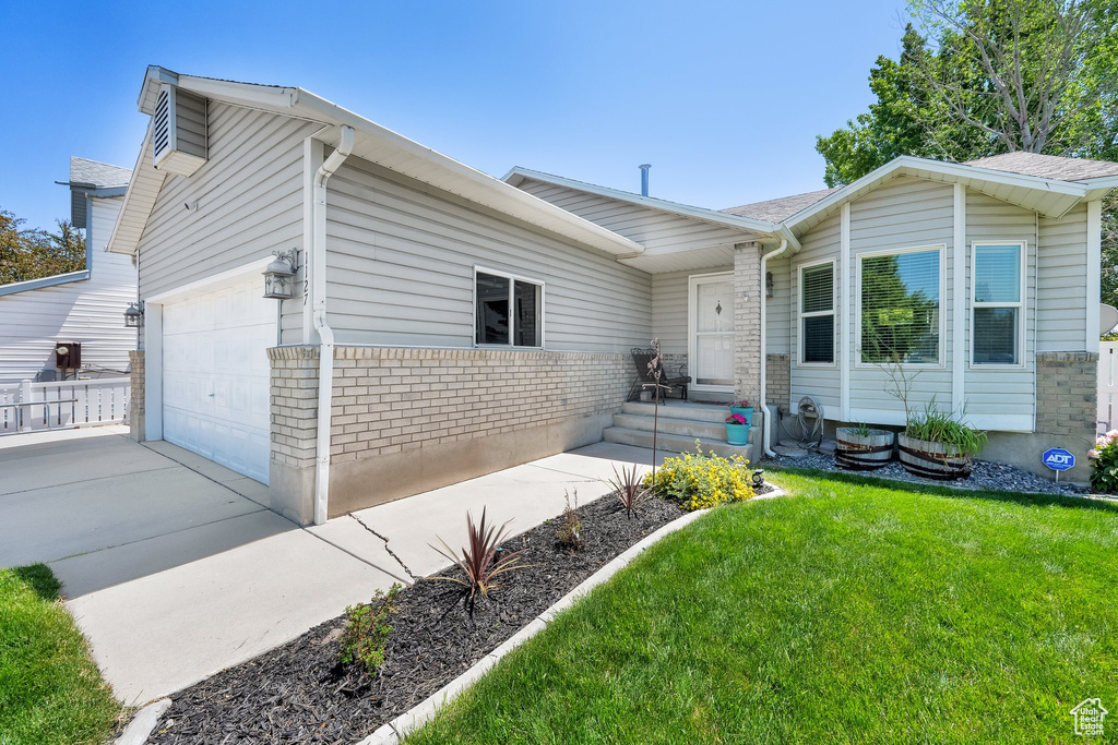 View of front of house featuring a garage, driveway, a front lawn, and brick siding