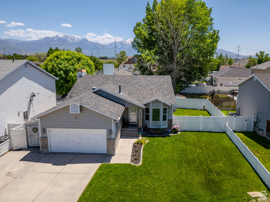 View of front facade featuring a mountain view, brick siding, an attached garage, concrete driveway, and a shingled roof