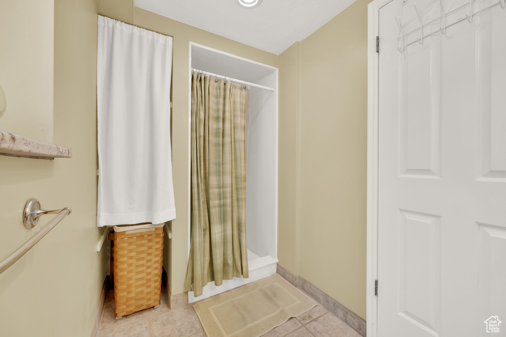 Bathroom with curtained shower and tile patterned flooring
