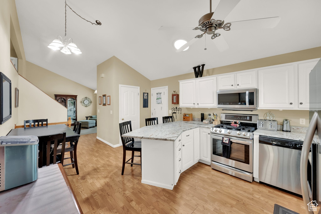 Kitchen with appliances with stainless steel finishes, a peninsula, ceiling fan, lofted ceiling, and a breakfast bar area
