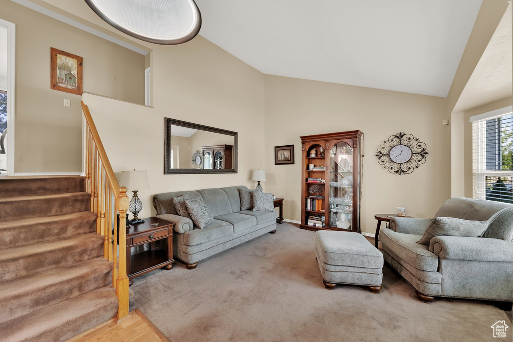 Carpeted living area with stairway, high vaulted ceiling, and baseboards