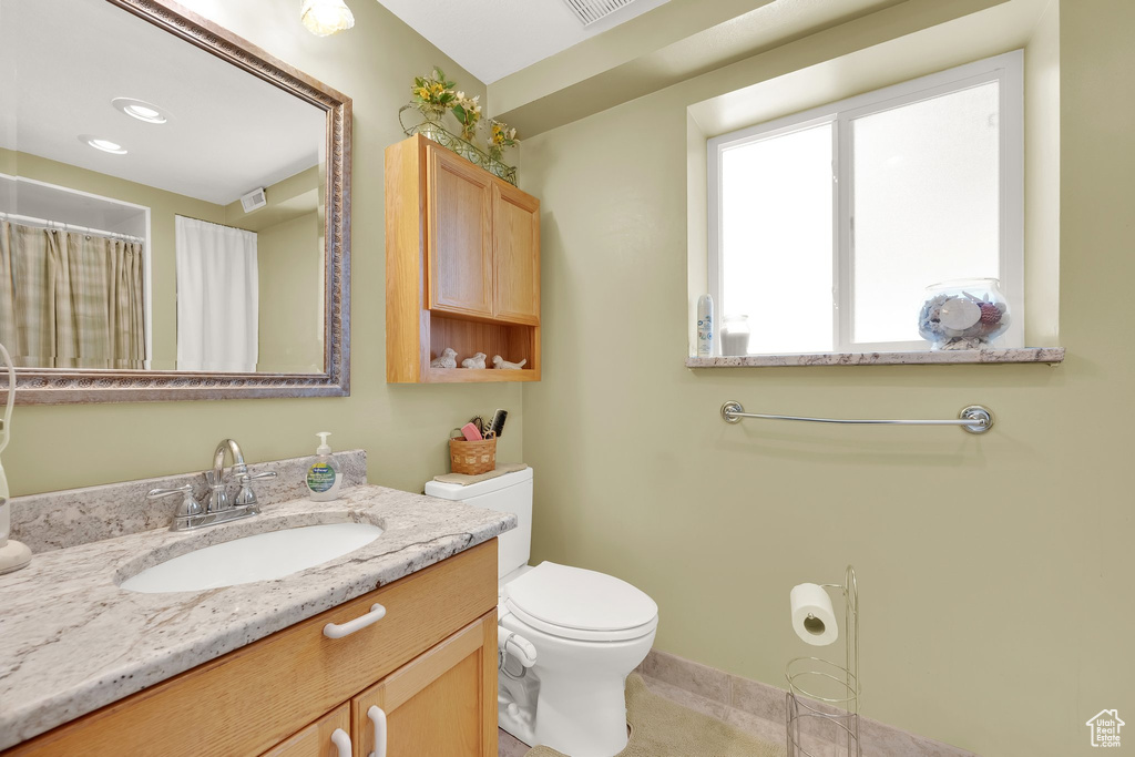 Bathroom with toilet, vanity, and baseboards