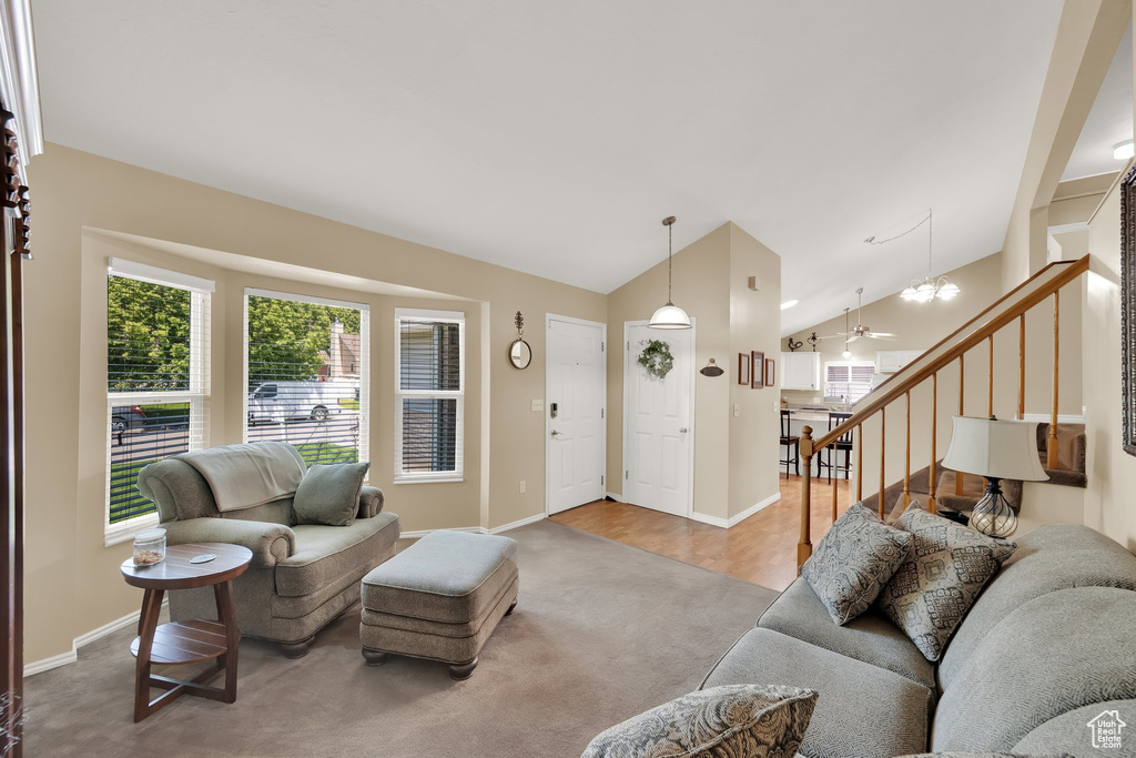 Carpeted living area featuring vaulted ceiling, stairs, baseboards, and a chandelier