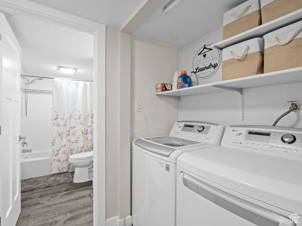 Washroom with wood finished floors and washing machine and clothes dryer