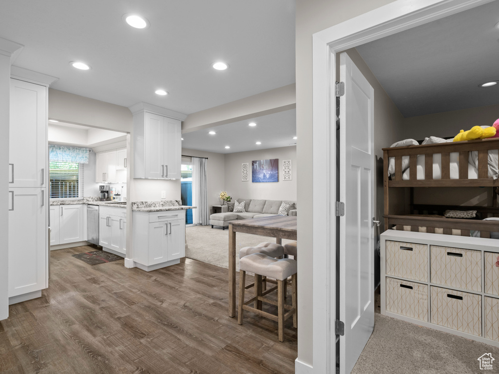 Kitchen with open floor plan, dark wood-style flooring, white cabinets, recessed lighting, and light stone countertops