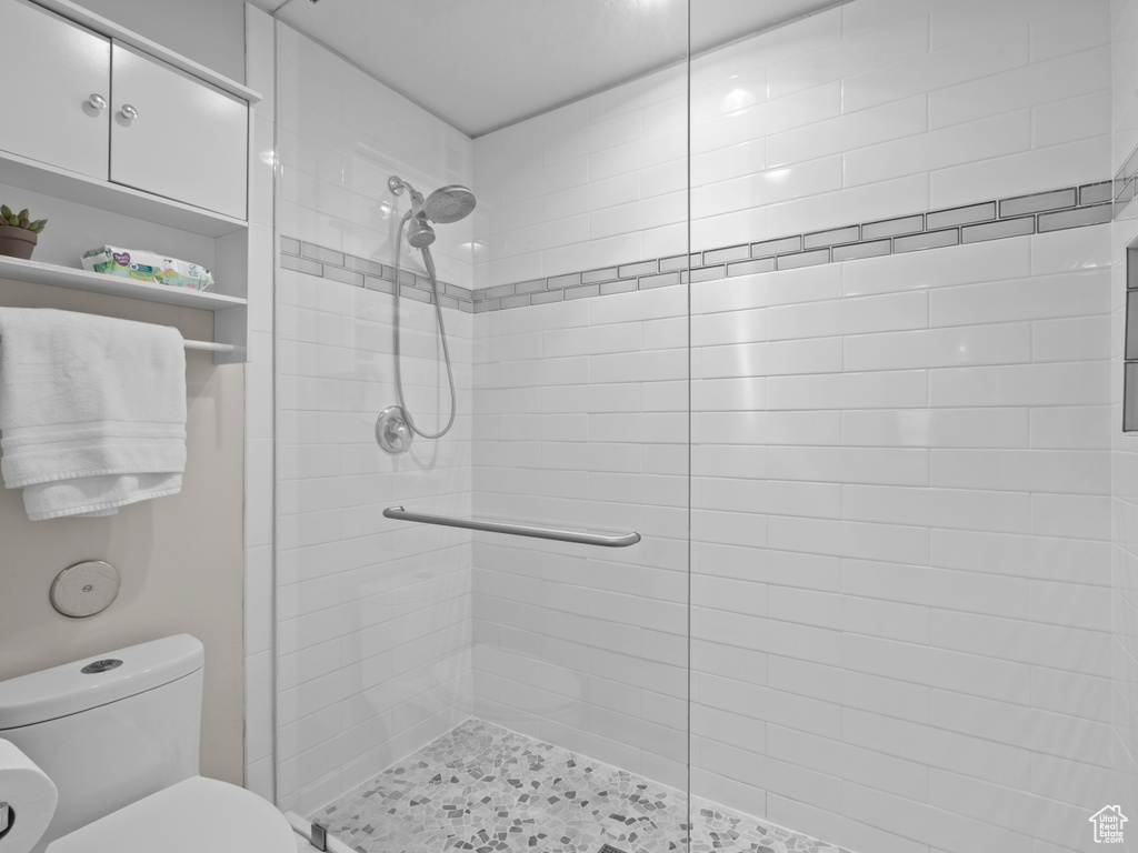 Full bath featuring tiled shower and toilet