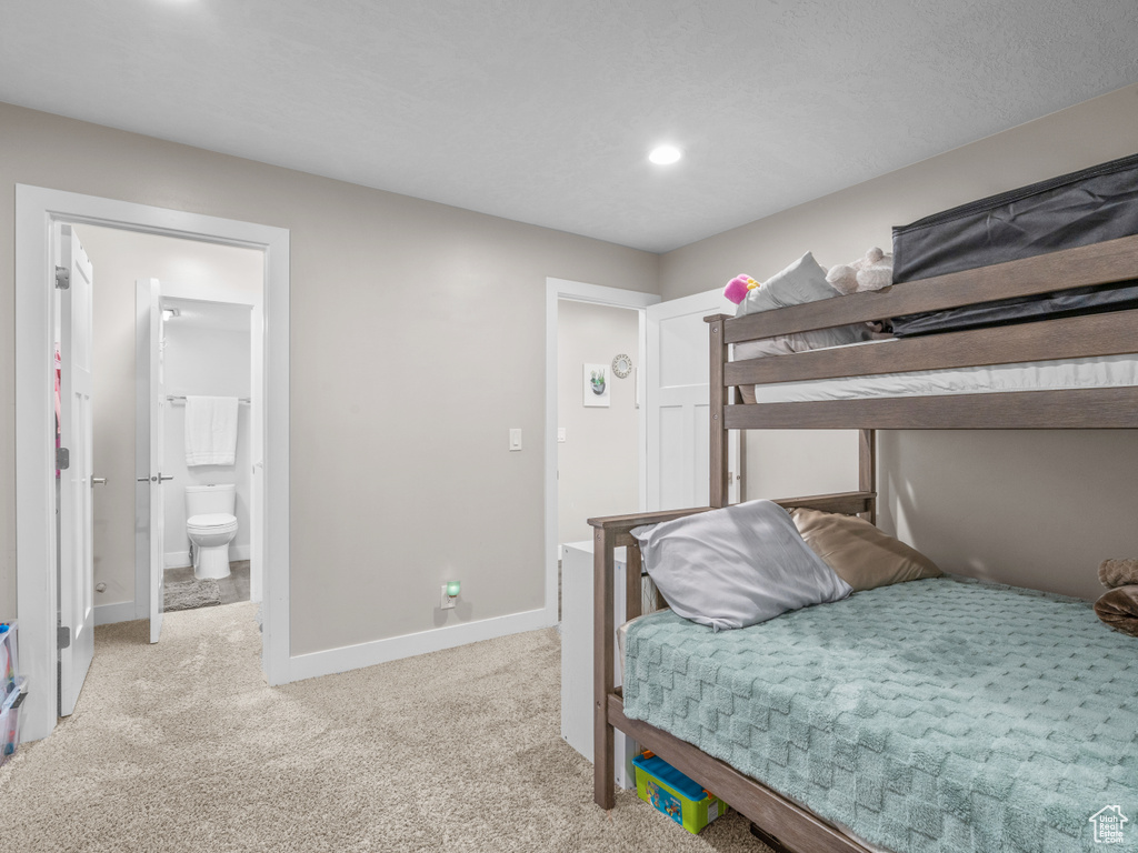 Carpeted bedroom featuring baseboards, recessed lighting, and ensuite bath