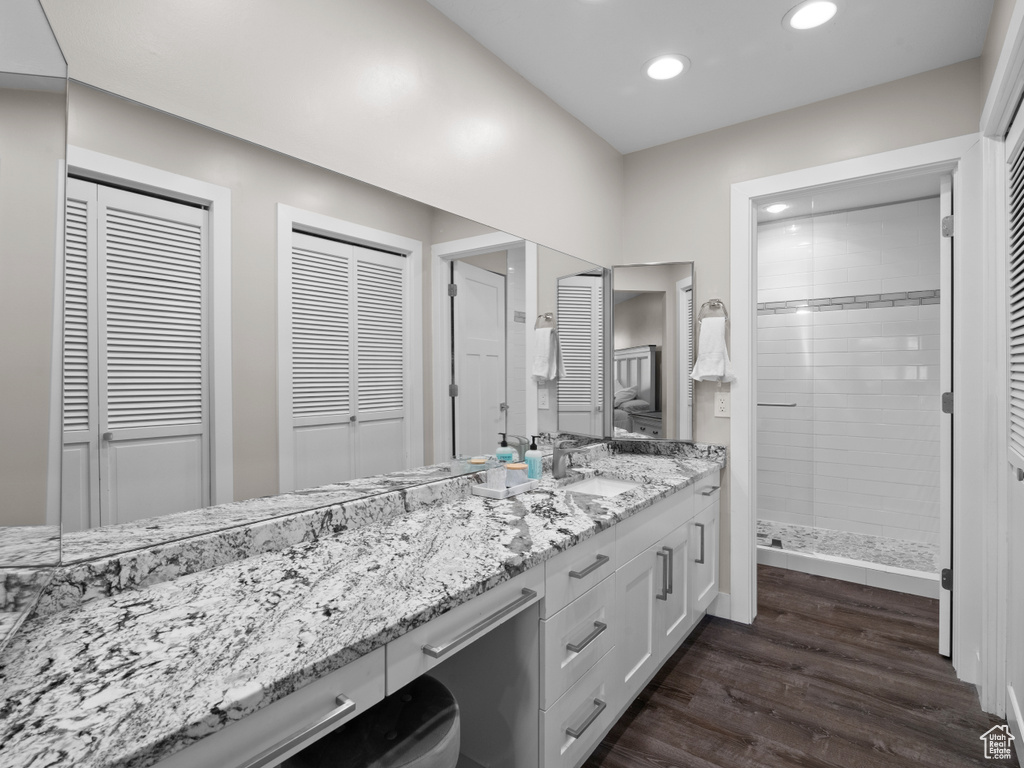 Bathroom with a closet, double vanity, recessed lighting, wood finished floors, and a stall shower