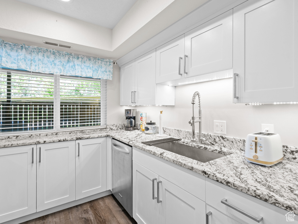 Kitchen with a sink, dishwasher, white cabinetry, dark wood-style flooring, and light stone counters