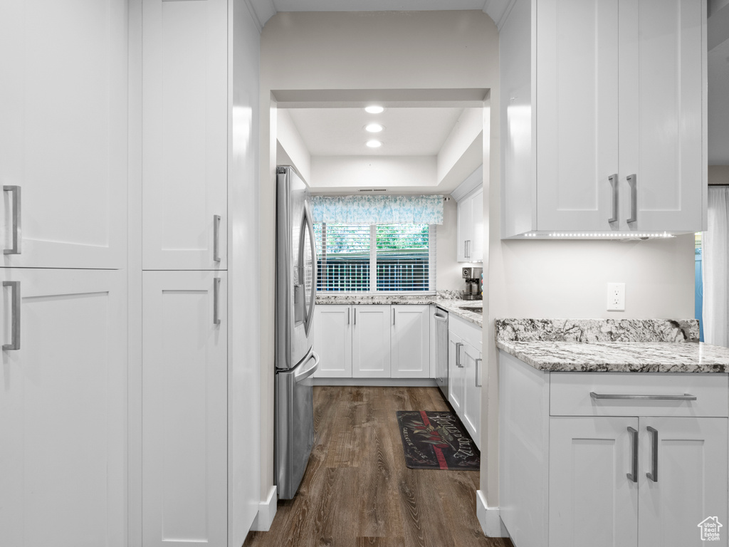 Kitchen featuring stainless steel appliances, dark wood-type flooring, white cabinetry, light stone counters, and recessed lighting