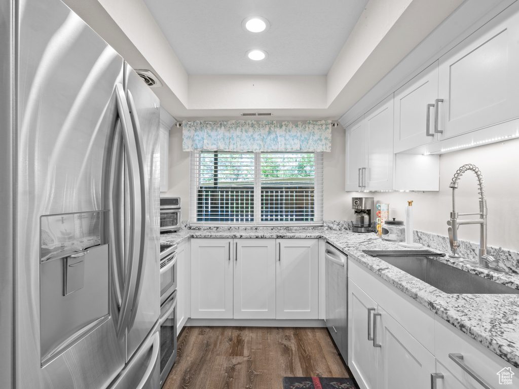 Kitchen featuring appliances with stainless steel finishes, a sink, white cabinetry, dark wood finished floors, and recessed lighting