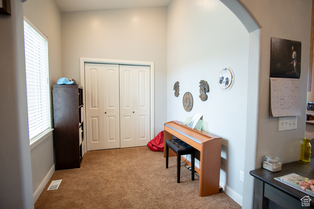 Home office with light colored carpet, plenty of natural light, and arched walkways