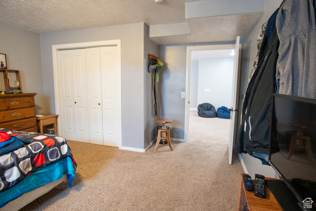 Bedroom with carpet flooring, a closet, a textured ceiling, and baseboards
