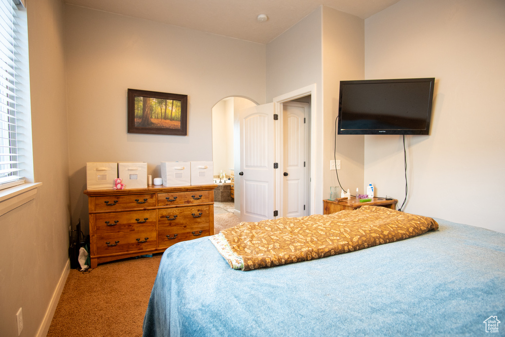 Carpeted bedroom with baseboards and arched walkways