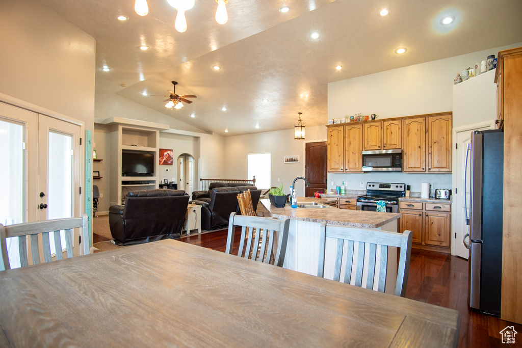 Kitchen featuring appliances with stainless steel finishes, a sink, light countertops, open floor plan, and a center island with sink