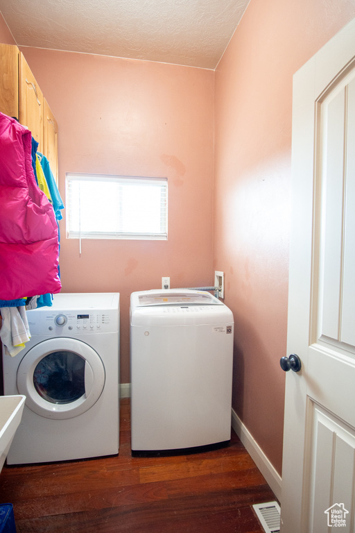 Laundry room featuring washing machine and dryer, wood finished floors, baseboards, and a textured ceiling