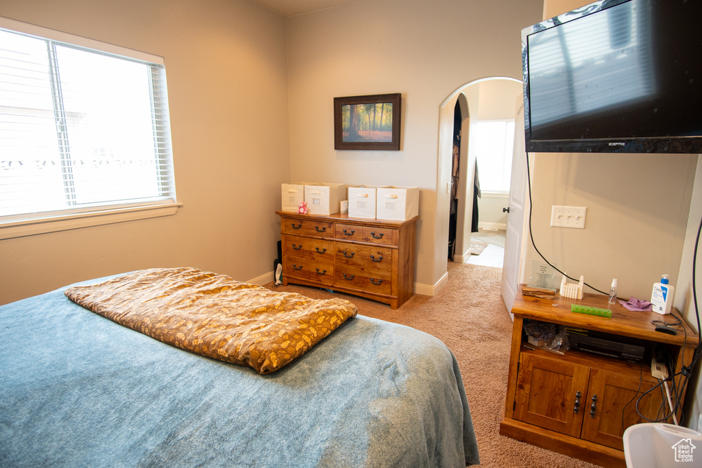 Bedroom with carpet, arched walkways, and baseboards