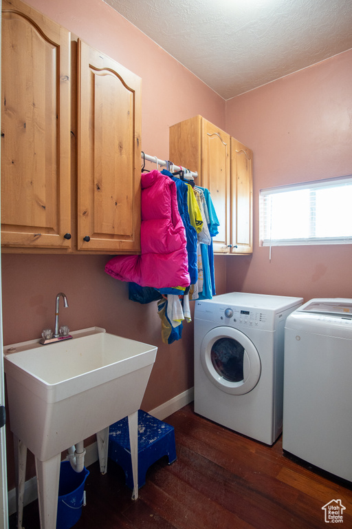 Laundry room featuring cabinet space, washer and clothes dryer, wood finished floors, a textured ceiling, and baseboards
