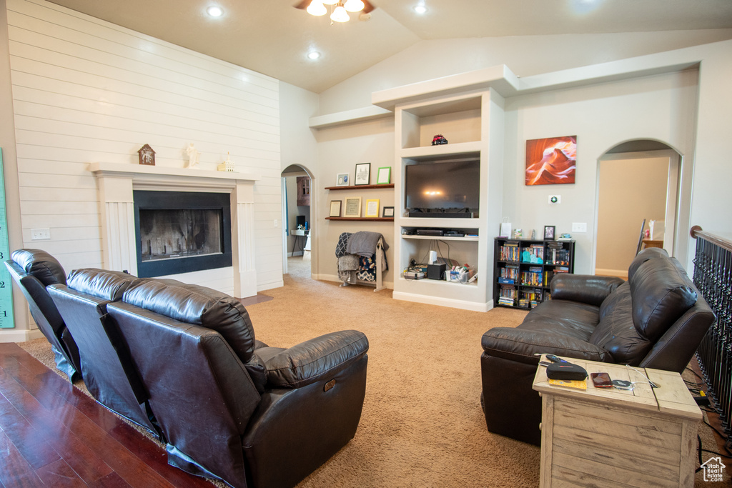 Living room featuring arched walkways, vaulted ceiling, built in features, a fireplace with flush hearth, and recessed lighting