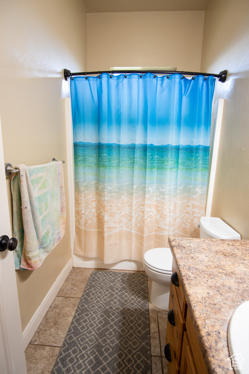Full bath featuring vanity, toilet, tile patterned flooring, baseboards, and shower / bath combo