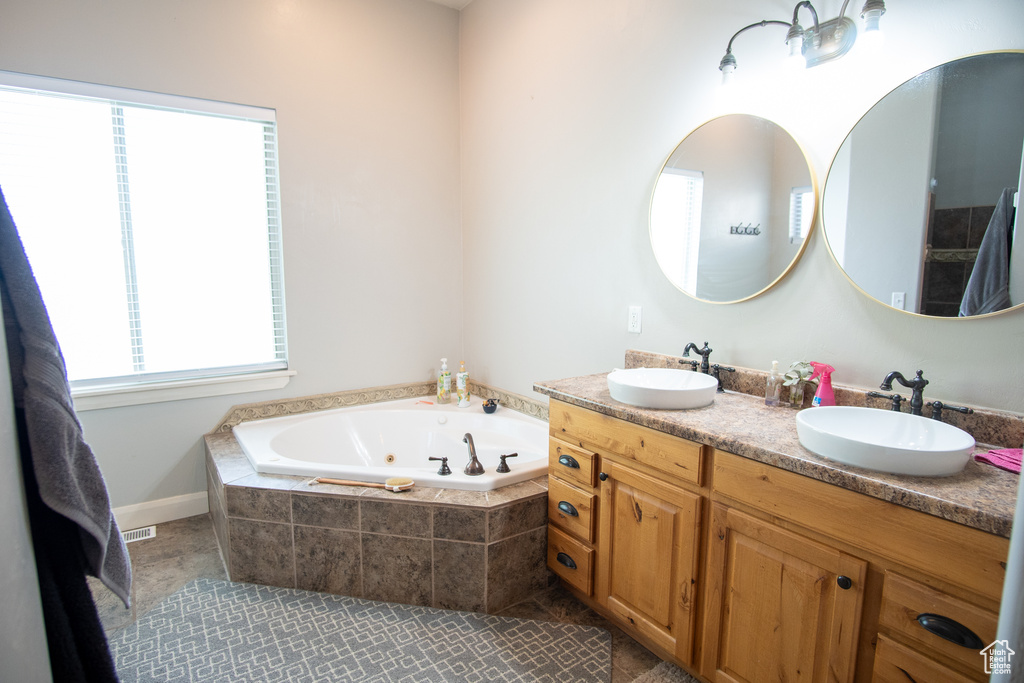 Bathroom featuring double vanity, a jetted tub, and tile patterned flooring