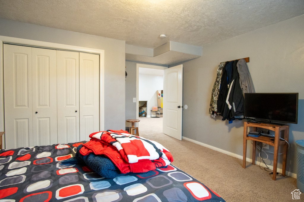 Bedroom with a textured ceiling, carpet flooring, a closet, and baseboards