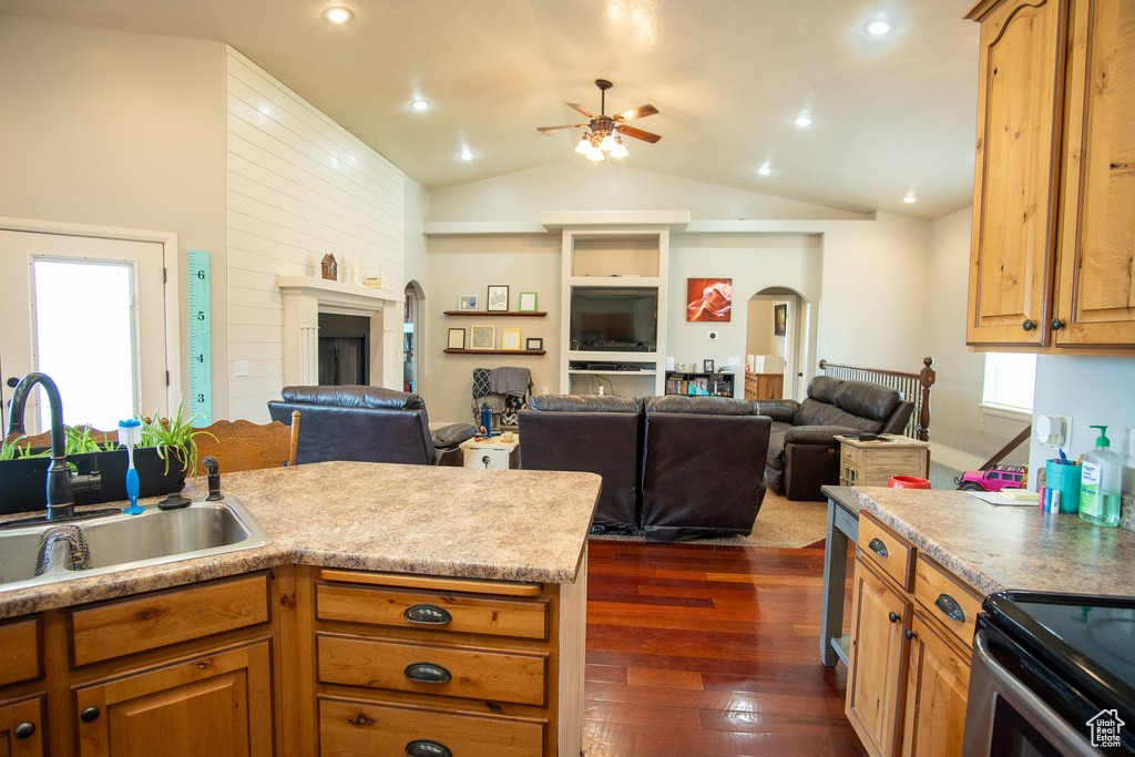 Kitchen featuring a ceiling fan, a sink, arched walkways, dark wood-style flooring, and open floor plan