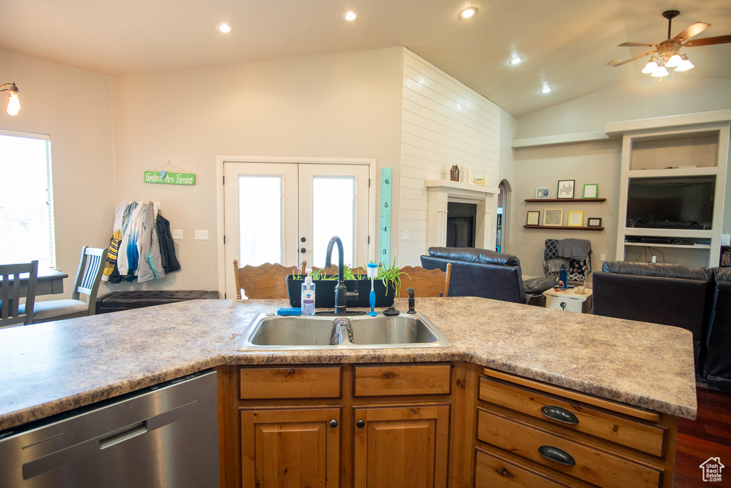 Kitchen with open floor plan, stainless steel dishwasher, a sink, ceiling fan, and brown cabinets