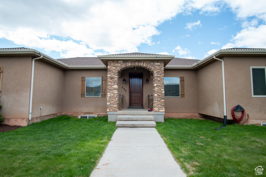 Property entrance with a yard and stucco siding