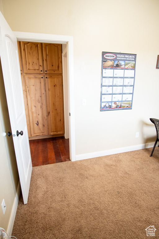Unfurnished bedroom with dark colored carpet and baseboards
