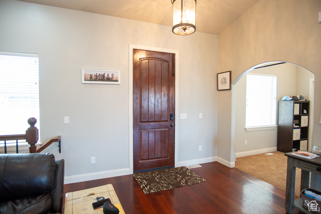 Entrance foyer featuring arched walkways, dark wood-style flooring, and baseboards