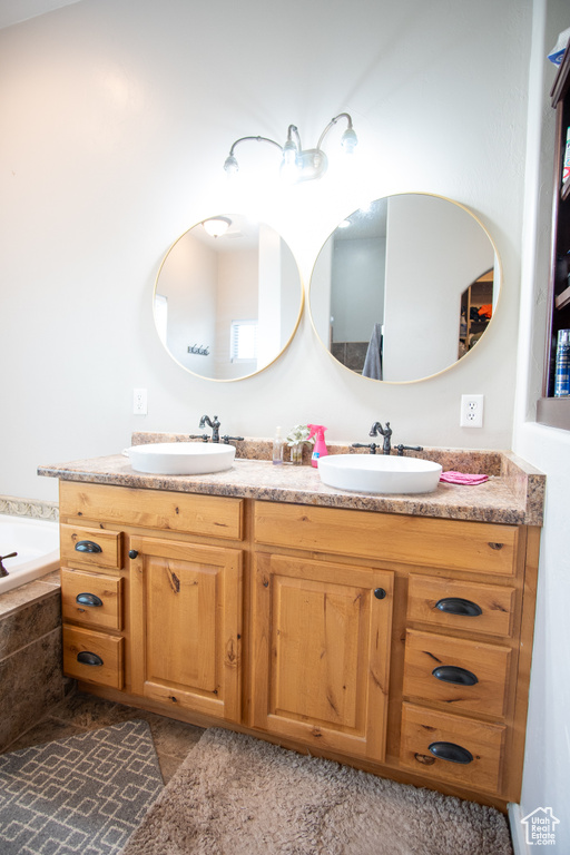 Bathroom featuring double vanity and tiled bath